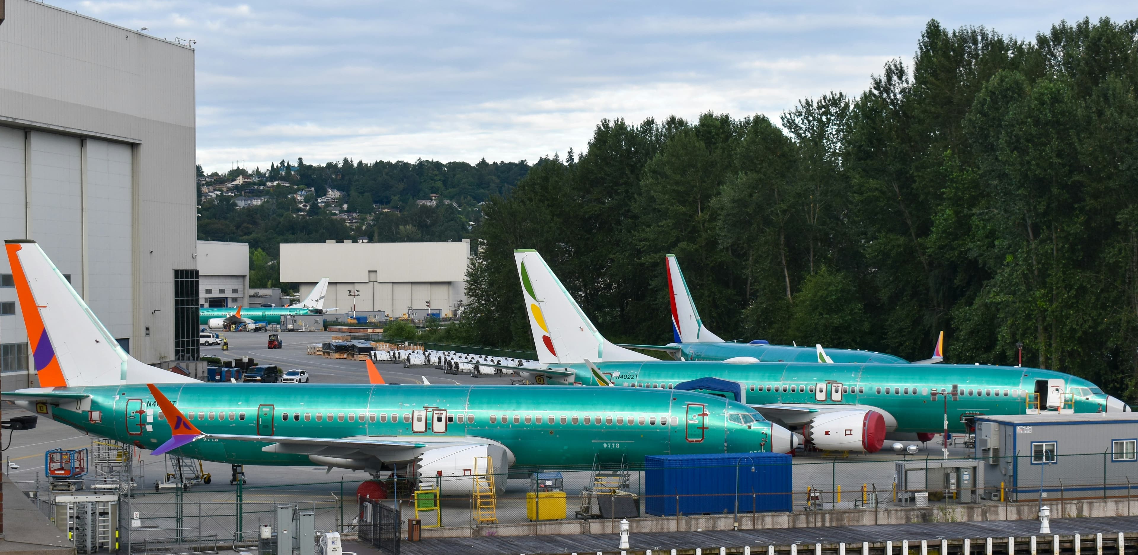 Unpainted airframes on a final assembly line beside a production hangar